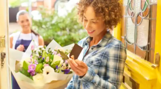 woman in checked shirt receiving a delivery of flowers at her door with the delivery woman in the background showcasing biosecurity on imported flowers